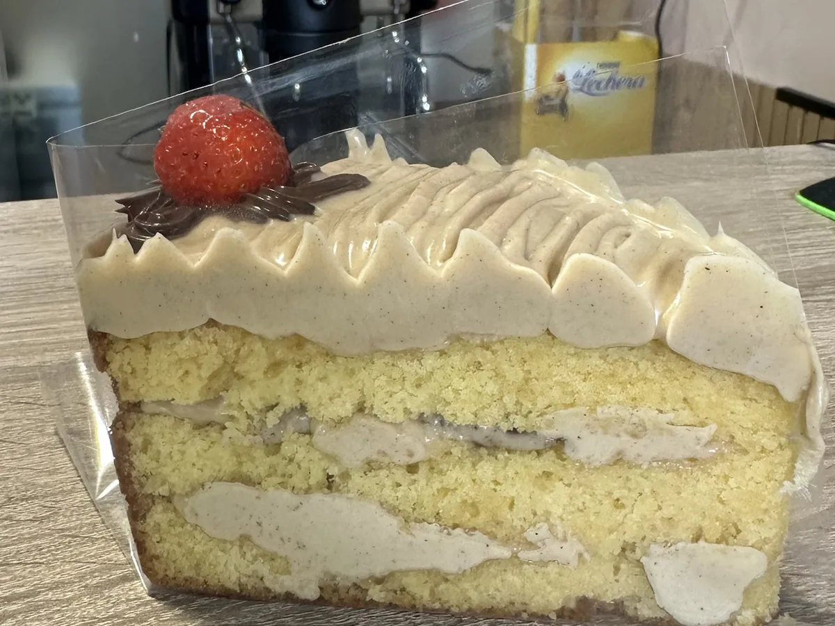 Porción de tarta de vainilla con crema de Kinder Bueno, fresa y chocolate encima